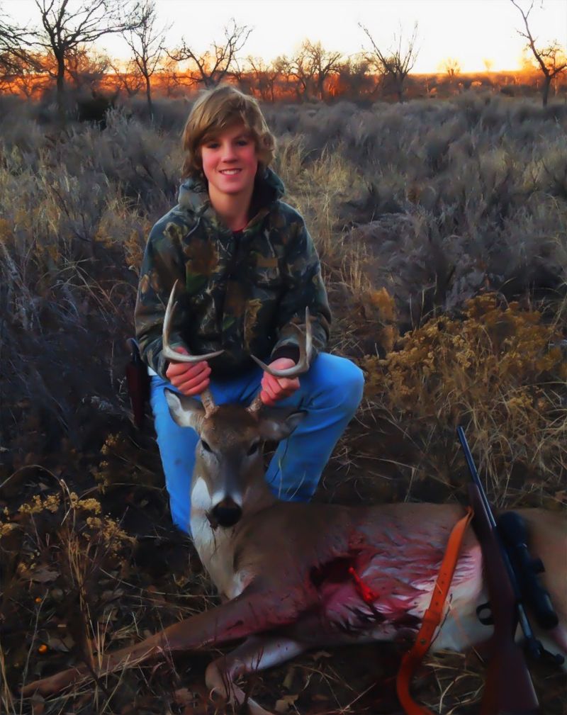 Bobby kneeling behind his first buck, a seven-point whitetail, at dusk in the Texas Panhandle